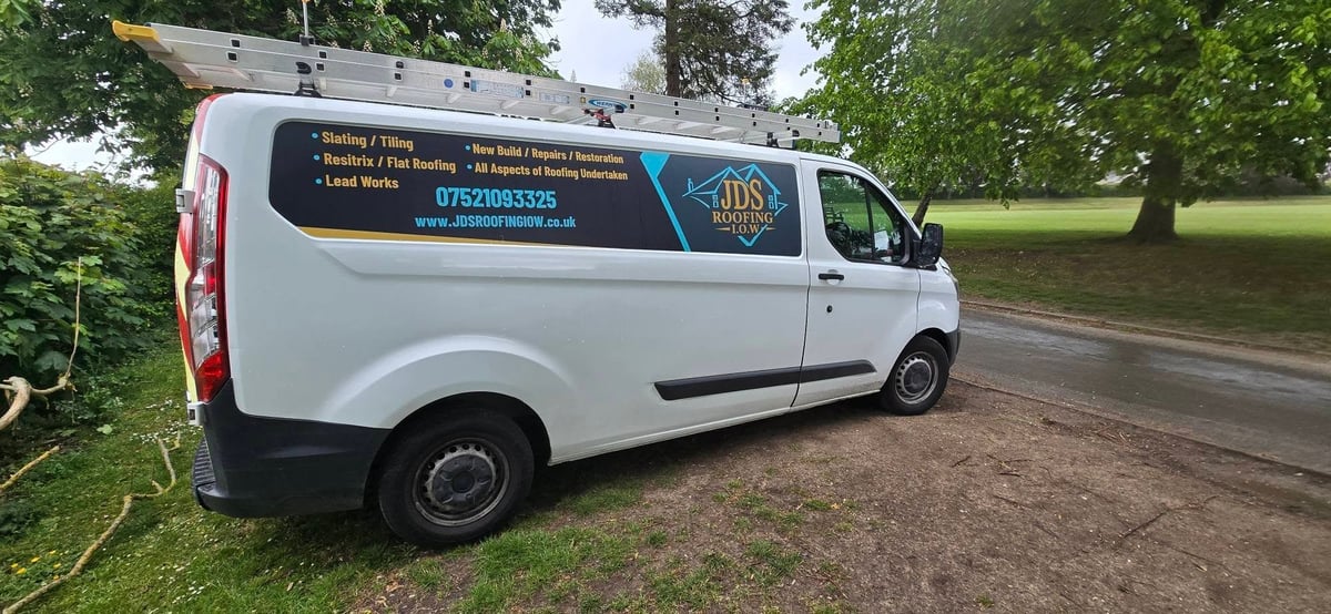 White service van parked on grass with contact information displayed on the side panel