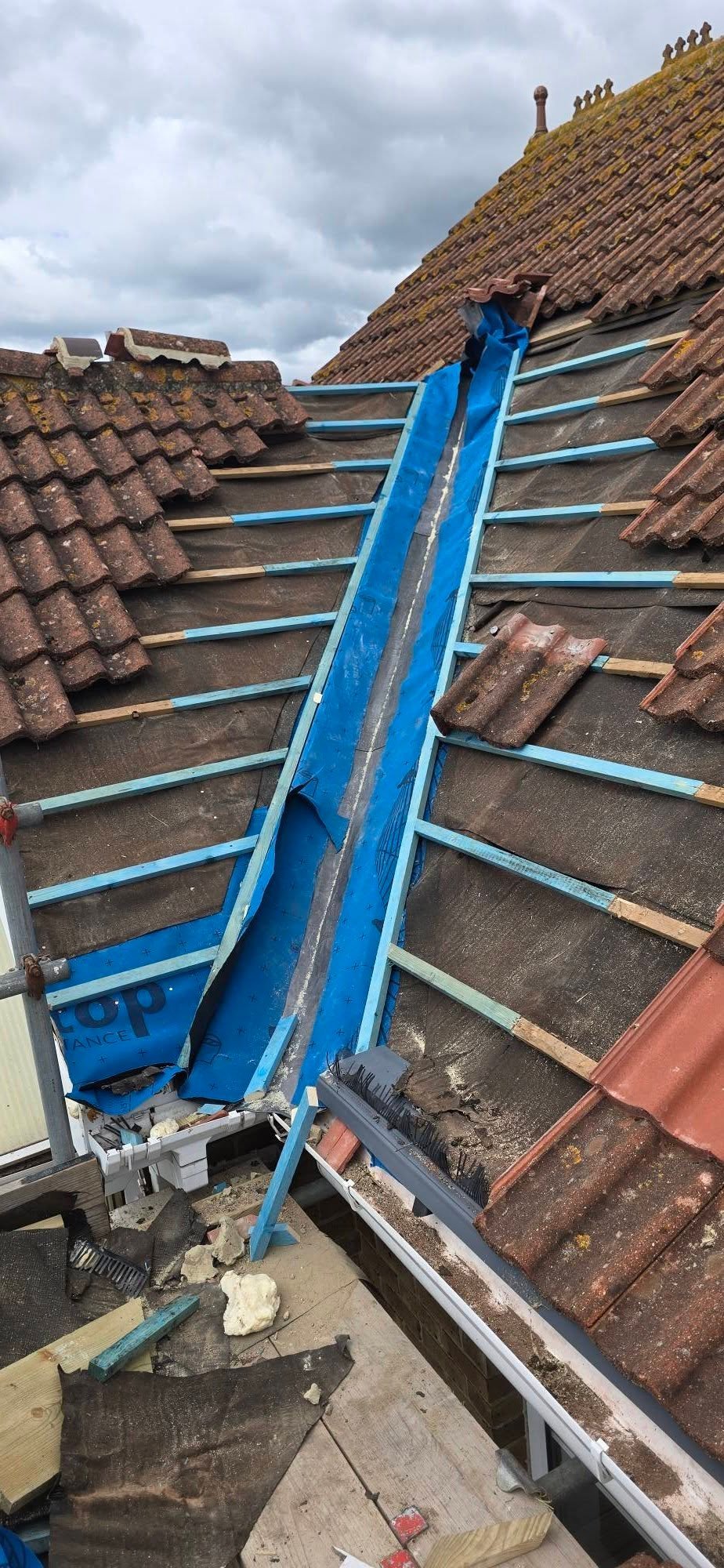 Blue roof scaffold structure installed on a sloped tiled roof during construction work